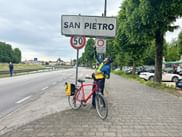 Cyclist in front of the town sign of San Pietro.