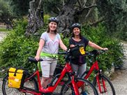 Two women with e-bikes in front of a tree