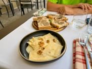 Frische Ravioli in Käsesauce und Brote mit Wildschweinfleisch garniert