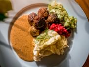 Teller mit schwedischen Köttbullar, cremiger Sauce, Kartoffelpüree, Gurkensalat, Preiselbeeren und frischem Dill.
