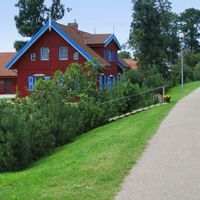 Red houses with blue shutters and gables next to a cycle path of the village Rusne