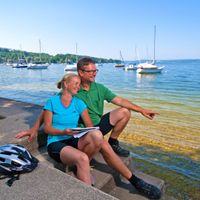 Cycling break of a couple on the shore of the Ammersee at the harbour of Herrsching