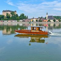 Blick vom Donauufer aus auf Grein, mit einem kleinen Holzboot im Vordergrund