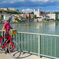 Radlerin bei einem Zwischenstopp auf einer Brücke mit Blick nach Passau