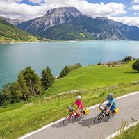 Zwei Radfahrer auf gut ausgebauten Radwegen am Reschensee mit Bergpanorama im Hintergrund