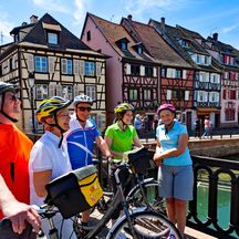 Radfahrer machen Pause am Kanal in Colmar mit butnen Fachwerkhäuser im Hintergrund