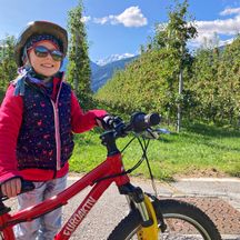 Child with bike in front of a natural backdrop