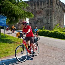 Radler fahren an Burgruine von Borghetto vorbei
