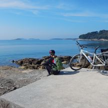Radfahrerin bei Radpause mit wunderschönem Ausblick auf das Meer