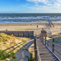 Strand mit Wellen, Strandhütten und Holzstiege