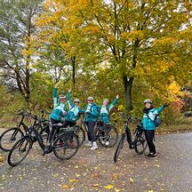 Radlergruppe vor herbstlichem Baum