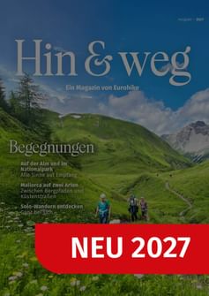 Cover des Hin & weg Magazins 2027 zeigt Wanderer auf grünem Alpenweg mit Bergen. Rotes Banner mit 'NEU 2027'.