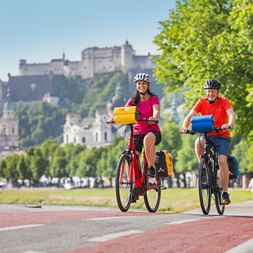Cyclists in Salzburg with fortress Hohensalzburg in the background