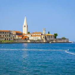 Küstenansicht der Altstadt von Poreč mit dem weißen Glockenturm der Euphrasius-Basilika und historischen Gebäuden an der blauen Adria.