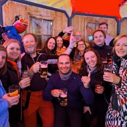 Large group of Eurohike team members in winter clothing celebrating together with drinks in an alpine lodge in Obertauern.