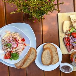 Traditionelle bayerische Brotzeit mit Wurst, Käse, Brot und Gemüse auf Holztisch. Mit Wurst, Schinken, Käse, Zwiebeln und Gurken.
