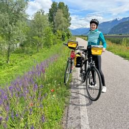 Cyclist on the Etsch cycle path with meadows and mountains in the background