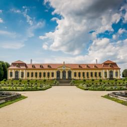 Schloss Großsedlitz bei Heidenau mit gelber Fassade und rotem Dach, formale Gärten mit Brunnen und geschnittenen Hecken zum Schlosseingang.