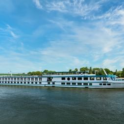 Weißes Flusskreuzfahrtschiff MS Switzerland fährt auf ruhigem Wasser bei blauem Himmel. Das mehrstöckige Schiff hat Fensterreihen und Sonnendeck.