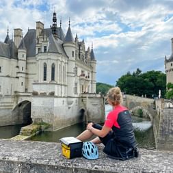 Radler blickt auf der Mauer sitzend auf Schloss Chenonceau