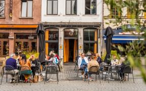 Außenterrasse der Brasserie de Cirque in Mechelen mit Gästen an Tischen auf einem Kopfsteinpflasterplatz, historische Gebäudefassaden im Hintergrund.