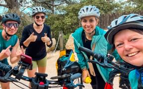 Vier Radfahrer mit Helmen machen ein Selfie während des Eurofun Betriebsausflugs auf Mallorca. Sie tragen türkisfarbene Jacken und lächeln.