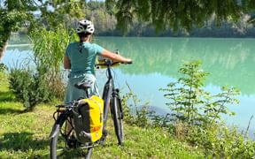 Radfahrerin steht an Fluss