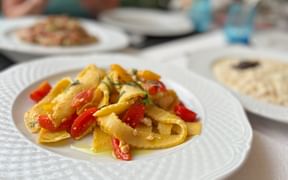 Pappardelle-Pasta mit roten und gelben Paprika auf einem weißen Teller, serviert während einer kulinarischen Radreise in der Prosecco-Region Venetiens.