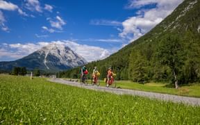 Drei Radfahrer auf einem der Radwege in Leutasch, mit Bergpanorama im Hintergrund