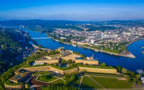 Luftaufnahme der Festung Ehrenbreitstein auf einem Hügel mit Blick auf den Zusammenfluss von Rhein und Mosel bei Koblenz und der Stadt darunter.