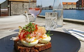 View of a loaf of bread with egg, shrimps, bacon and cress, with the harbour in the background
