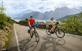 Zwei Radfahrer auf einer Straße oberhalb von Torbole mit Blick auf den Gardasee