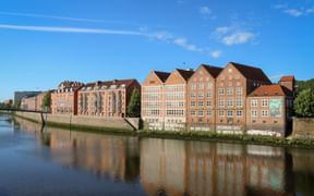 Historische Backsteingebäude des Weserburg Museums für moderne Kunst an der Weser in Bremen, spiegelnd im ruhigen Wasser unter blauem Himmel.
