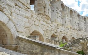 Steinbögen und Mauern des antiken römischen Amphitheaters in Arles, Provence, mit verwitterten Kalksteinblöcken und architektonischen Details.