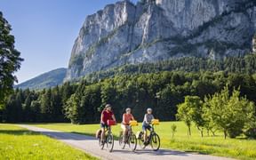 Drei Radfahrer radeln am Mondsee an der Drachenwand vorbei