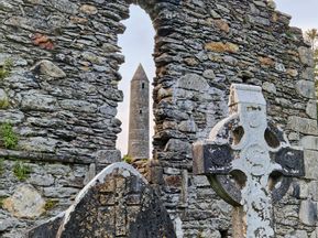 Der Friedhof von Glendalough mit Blick durch eine Steinmauer auf den Rundturm