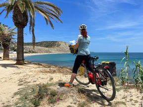 Radfahrerin beim Lesen des Routenbuchen am Praia de Luz