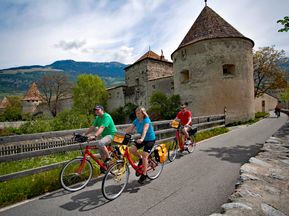 Radfahrer fahren an kleiner Burg vorbei