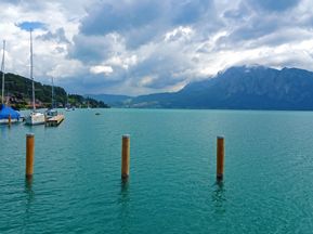 Boats on the turquoise-blue lake with mountains in the background