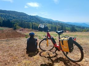 Cyclist next to e-bike with a view of the Tuscan Appennines