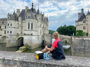 Radfahrerin sitzt auf der Brücke von Schloss Chenonceau