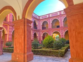 Green inner courtyard surrounded by colourful Spanish-style monastery walls