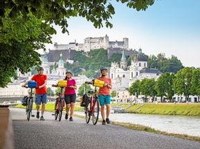 Radfahrer in Salzburg mit Blick auf die Festung Hohensalzburg