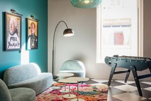 Colorful lounge at Hotel Labe Tours with turquoise sofa, foosball table, checkered floor, and pop art posters on teal wall.