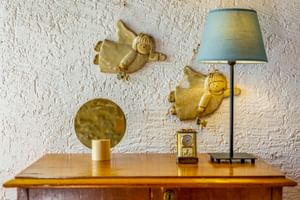 Wooden dresser with lamp, mirror, and angel figurines on white textured wall at Le Valli Agriturismo in Casciana Terme, Italy.