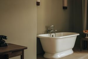 White freestanding bathtub with chrome fixtures in bathroom at Parkhotel Mondschein Bozen, featuring beige walls and wooden flooring.