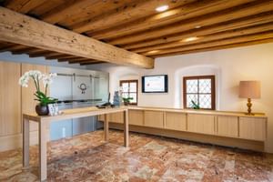 Moderne Rezeption mit Holzbalkendecke, Marmorboden, hellen Holzmöbeln und weißen Orchideen im Hotel Post am See in Traunkirchen.