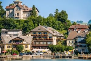 Seeblick auf Hotel Post am See in Traunkirchen mit traditioneller Alpenarchitektur, Holzbalkonen und Booten am Steg.