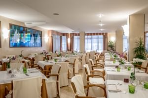 Elegant dining room at Du Lac et Bellevue in Bardolino with white-clothed tables, wooden chairs, green glassware, and large windows.