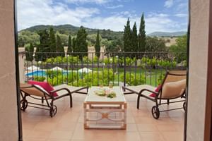 Terrasse mit Liegestühlen und Tisch mit Blick auf Pool, Garten, Zypressen und mallorquinische Hügel der Finca Son Roig.